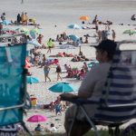 Gente en la playa con mascarillas